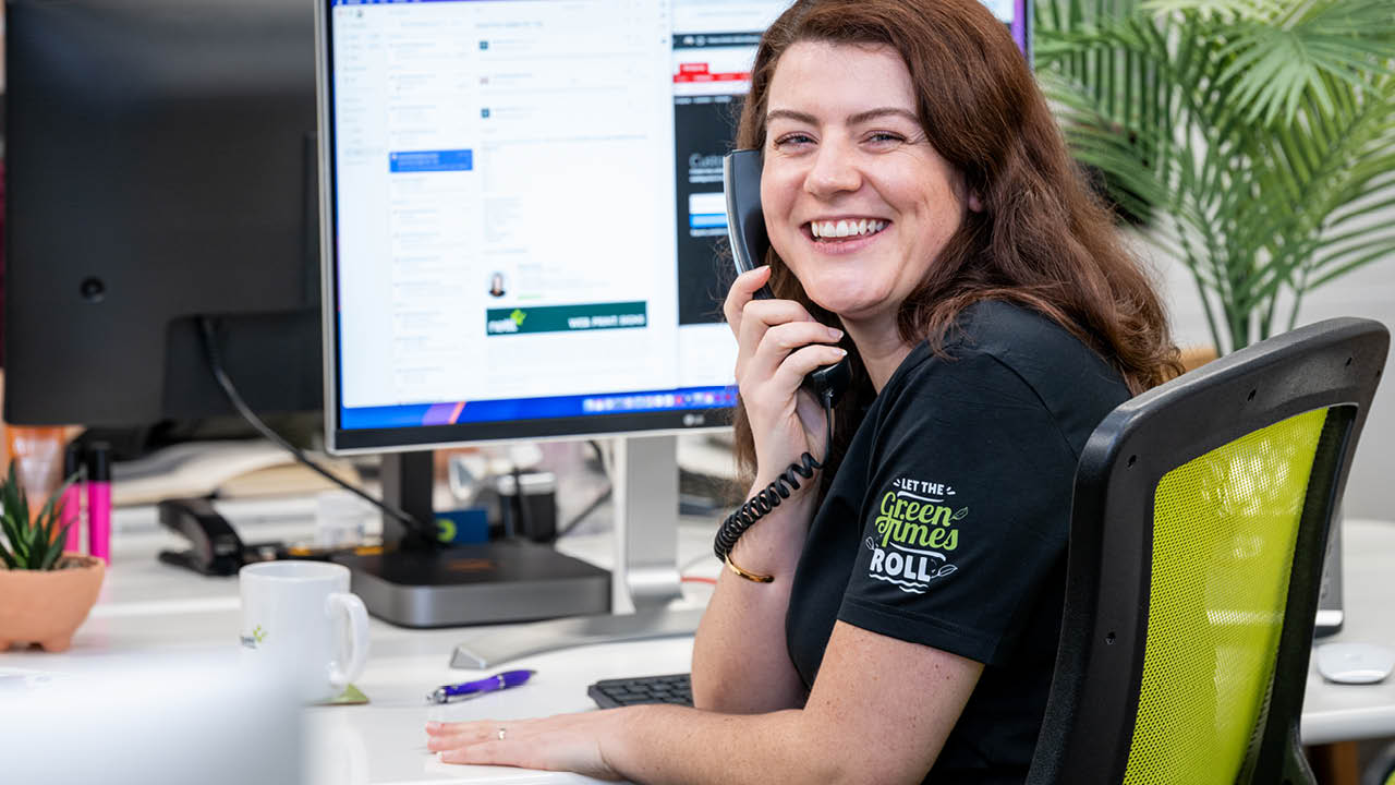 An image of three Nettl employees working on computers. There are two at a foreground table, with one person in the background.