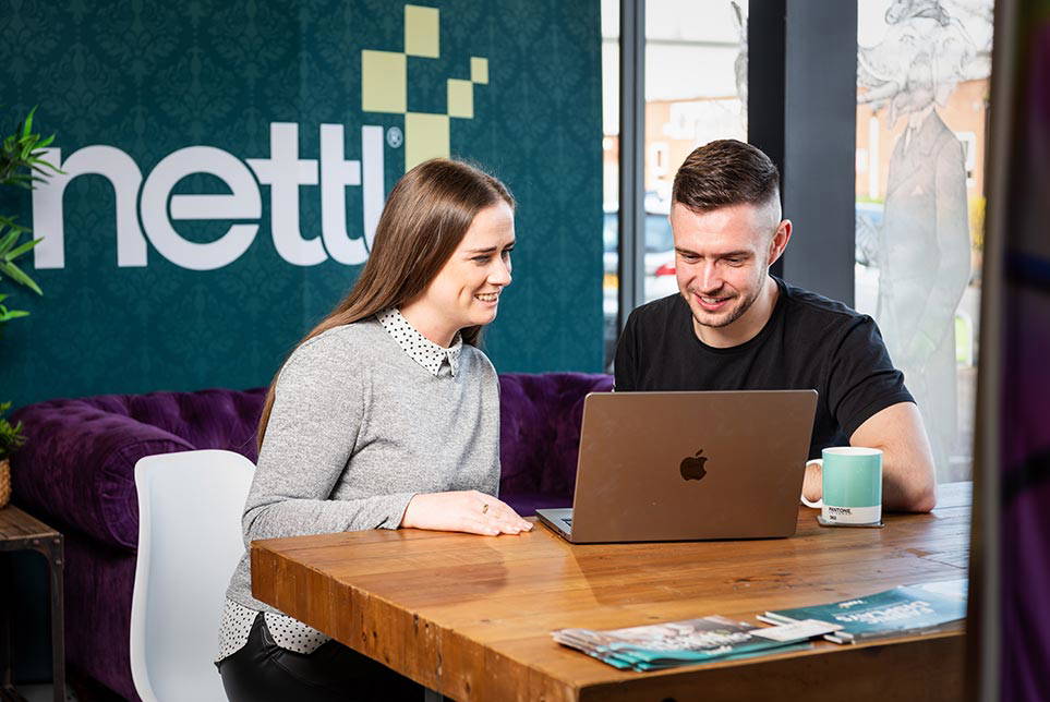 Two people, a Nettl employee and a client, working through a design on a laptop.