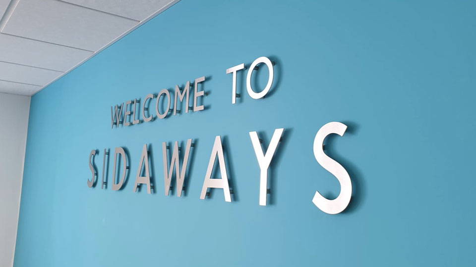 A wall with a mounted logo in silver.