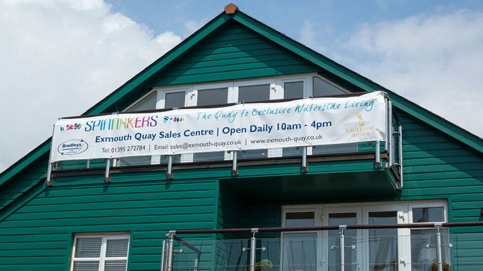 A teal building with a banner print on the front top of the building.