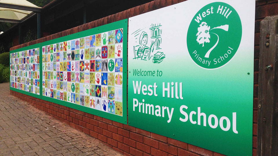 A sign done for a school that spans a large, brick wall